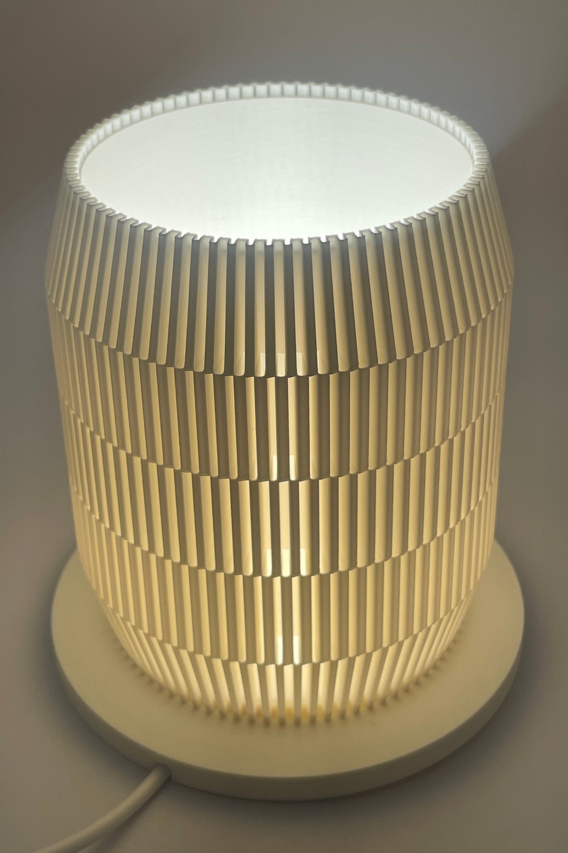 Modern lampskärm i cylinderform med geometriskt rutmönster som sprider ljus jämnt.